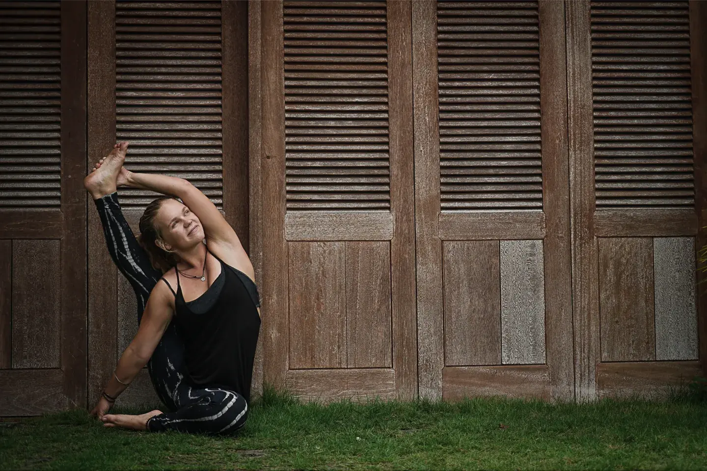 Maria Frisch practicing yoga in front of wooden shutters