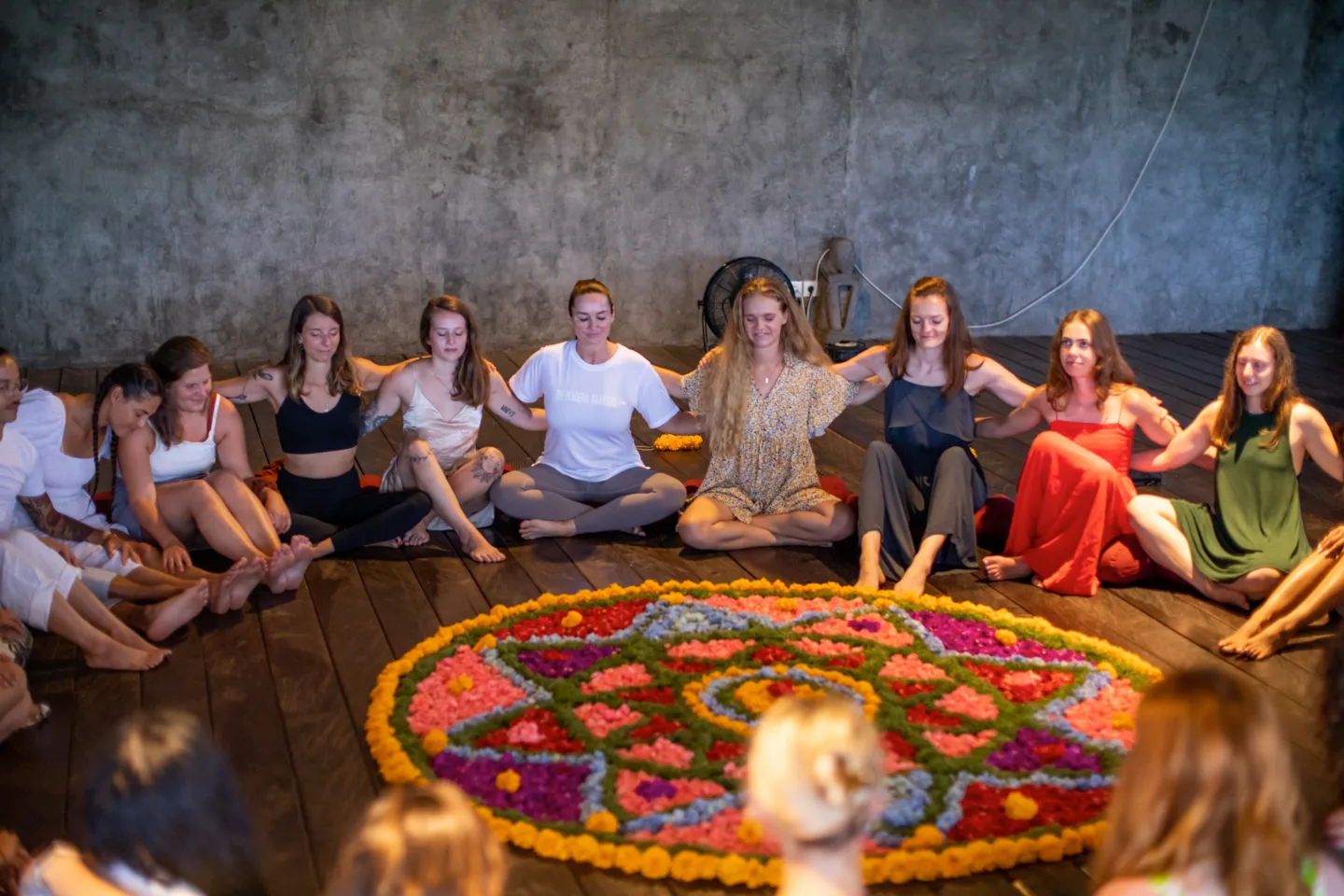 Women seated together around a flower mandala during teacher training